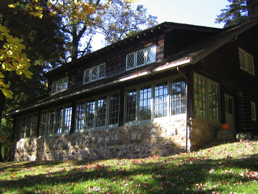 A craftsman home with a lot of windows, shaded by trees